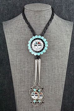 This mother of pearl, turquoise, onyx, coral and sterling silver inlay Zuni Sunface shaped bolo tie was made by Navajo silversmith Bryant Othole. The back is signed.Tie Length: 22 1/2"Length: 2"Width: 2"Tips:Length: 4 1/4"Width: 1 1/8"Free shipping on all orders! We ship with USPS and always include tracking. All orders ship within a day of payment.Returns are accepted up to 30 days after you receive your order. Just send us a message. Our shop offers cash back or store credit. The item must be Adjustable Artisan Jewelry With Inlay, Tie Length, Bolo Tie, Multi Stone, Mother Of Pearl, Onyx, Coral, Turquoise, Sterling Silver