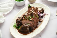 a white plate topped with meat covered in sauce and garnished with green onions