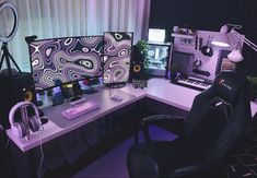 a computer desk with two monitors, keyboard and headphones on it in front of a window