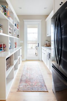 a kitchen with white cabinets and an area rug in front of the door that is open