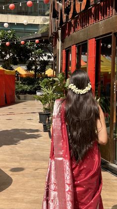 a woman in a red sari walking down the street with her back to the camera