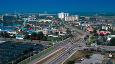 an aerial view of a city with lots of traffic on the road and buildings in the background