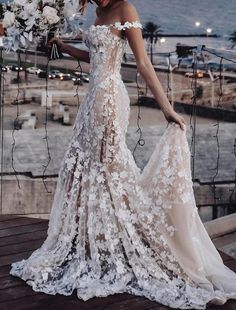 a woman standing on top of a wooden deck wearing a dress with flowers in it