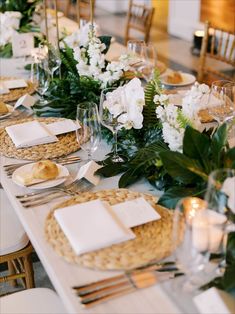 the table is set with white flowers and greenery