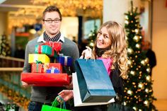 a man and woman holding shopping bags in front of a christmas tree