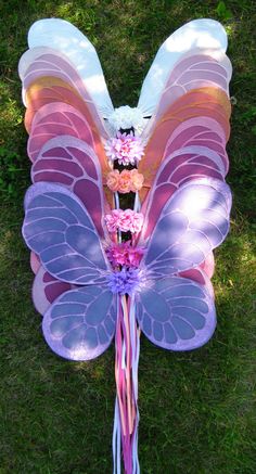 a large butterfly shaped kite with flowers on it's wings is laying in the grass