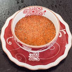 a red and white plate topped with a bowl filled with ground spices on top of a table