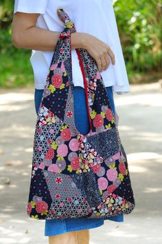 a woman is holding a large bag with flowers on it and she has her hands in the pocket