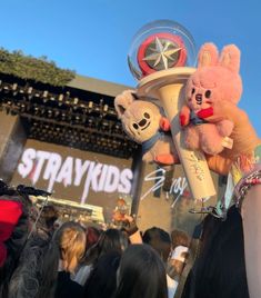 two stuffed animals on top of a pole in front of a crowd at a festival