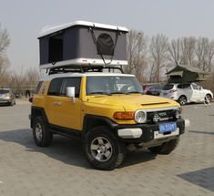 a yellow toyota fj cruiser parked in a parking lot with an awning on top