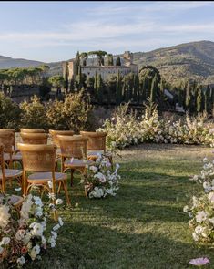 chairs are set up in the middle of an outdoor garden with flowers and greenery