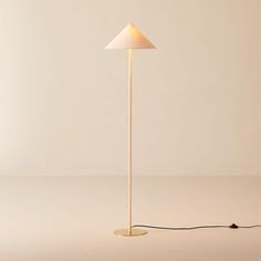 a floor lamp with a white shade on it and a cord plugged into the base