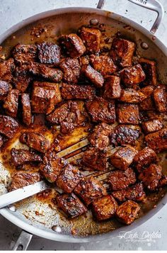 the meat is being cooked in a skillet with tongs and seasoning sugar