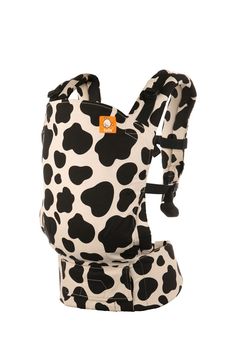 a black and white cow print baby carrier with orange buttons on the front, sitting against a white background