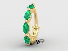 a gold ring with three emerald stones on the side and an oval shaped band around it