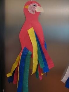 a colorful bird hanging from the side of a refrigerator door next to another stuffed animal