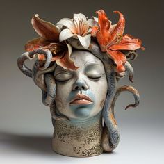 a ceramic head with flowers on it's head and an orange flower in its hair