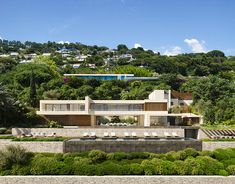 an aerial view of a modern house in the hills with trees and bushes surrounding it