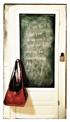 a chalkboard with a handbag hanging on the front door to someone's house