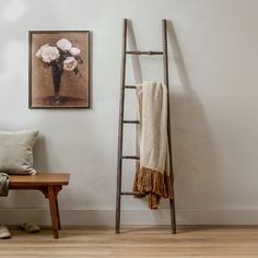 a wooden ladder leaning against a wall next to a bench with a flower vase on it