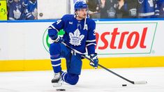 a hockey player in blue uniform skating on the ice with his stick and head gear