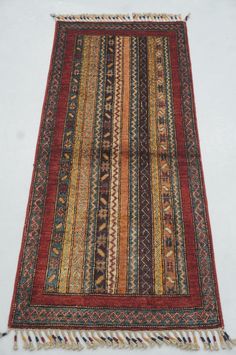 an old rug with multi colored stripes and fringes on the bottom is laying on a white surface