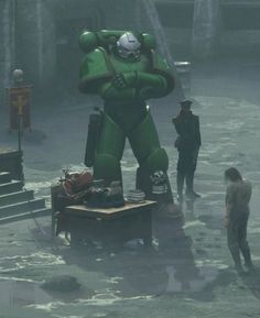 an inflatable green robot standing on top of a wooden platform next to people