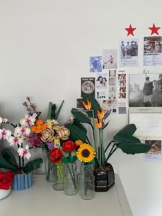 several vases with flowers are sitting on a table in front of pictures and photos