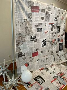 a large sheet of newspaper sitting on top of a hard wood floor next to a white balloon