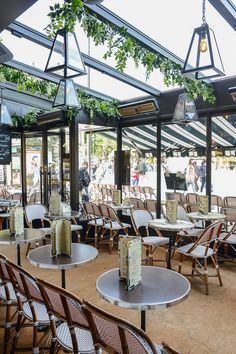 tables and chairs are set up in an enclosed area with lots of greenery hanging from the ceiling