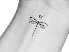 a small dragonfly tattoo on the back of a woman's left arm with a heart