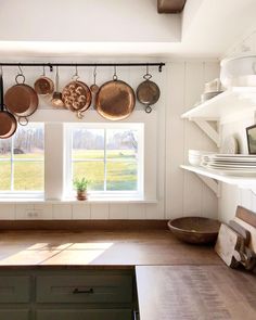 pots and pans are hanging on the wall in this kitchen