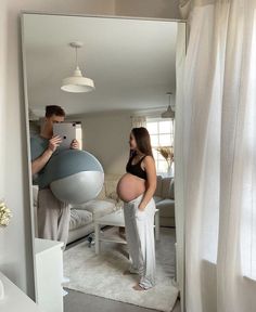 a man and woman standing in front of a mirror with a ball on the floor