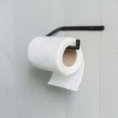 a roll of toilet paper is hanging on the wall next to a black hook with a handle