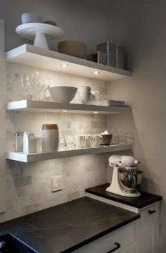 a kitchen with white shelves filled with dishes and cups on top of the countertop