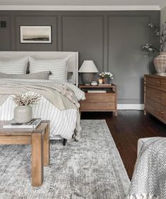 a bedroom with gray walls and white bedding, two nightstands and a large rug on the floor