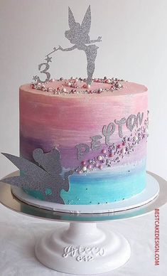 there is a cake decorated with pink, blue and purple frosting on the top