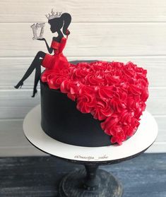 a black and white cake with red flowers on it, featuring a woman in a dress