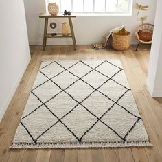 a white and black area rug in the corner of a room next to a window