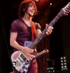 a man with long hair playing an electric guitar