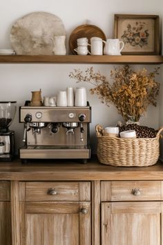 a coffee maker sitting on top of a wooden counter next to a basket filled with cups