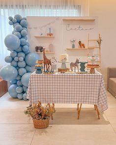 a baby's first birthday party with blue balloons and giraffes on the table