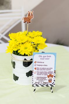 yellow flowers are in a white vase with a sign