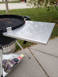 an outdoor grill is shown with newspaper on the side and grass in the back ground