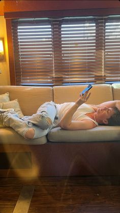 a man laying on top of a white couch next to a wooden window sill