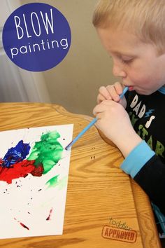 a young boy painting with watercolors on a piece of paper that says blow painting