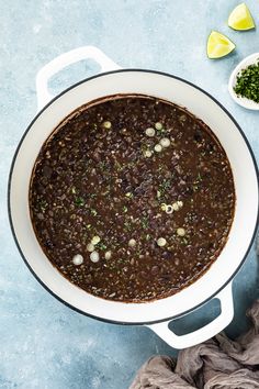 a pot filled with chili and beans next to a bowl of cilantro peppers