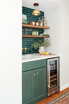 a kitchen with green cabinets and shelving above the sink is filled with wine bottles