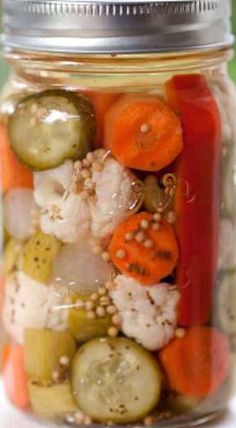 a jar filled with pickles, carrots and cucumbers