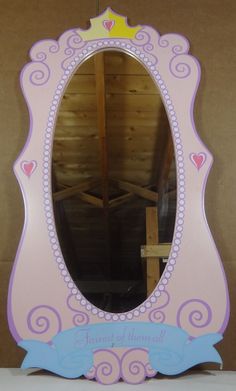 a pink and blue mirror sitting on top of a wooden table next to a wall